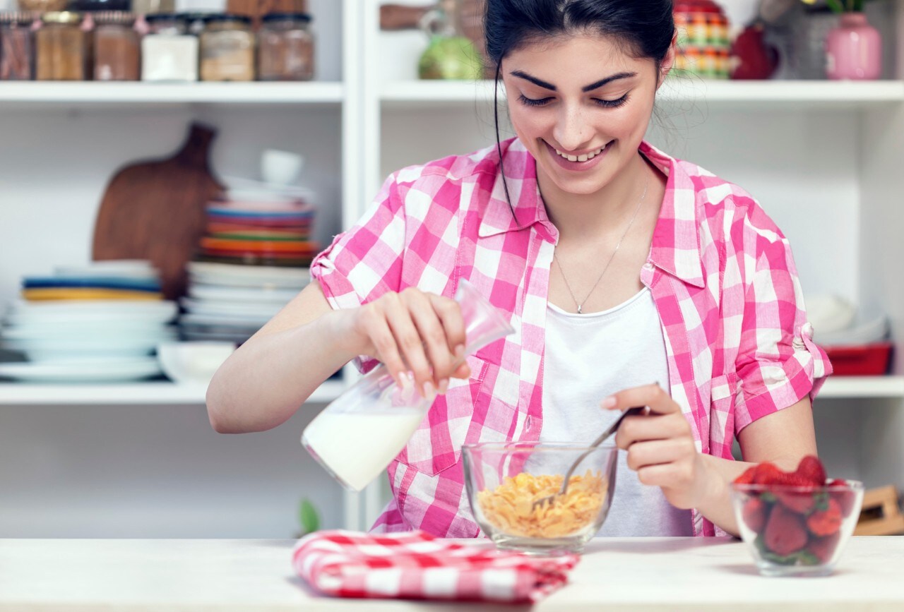 Young Beautiful Girl Preparing Cornflakes for the Breakfast In Kitchen