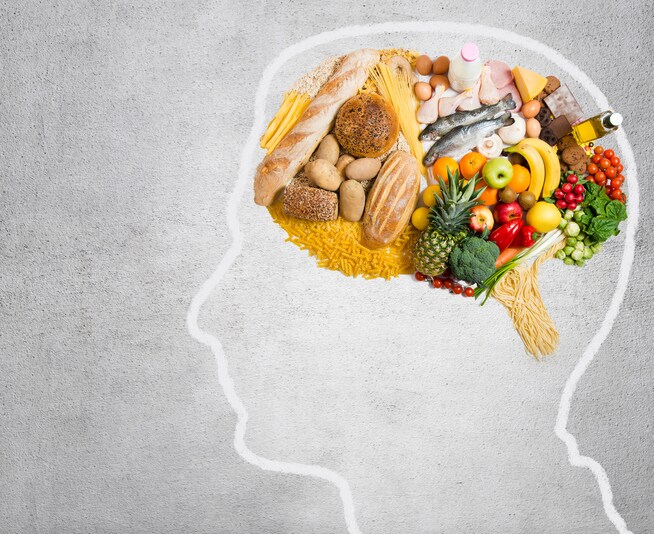 Human head shape with variety of different food ingredients on gray background